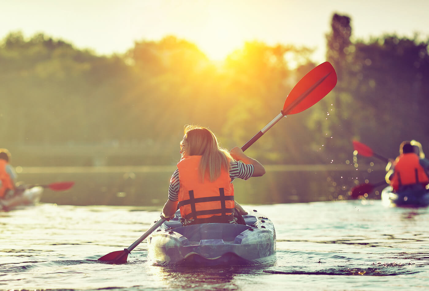 A girl kayaking with a group of people at sunset