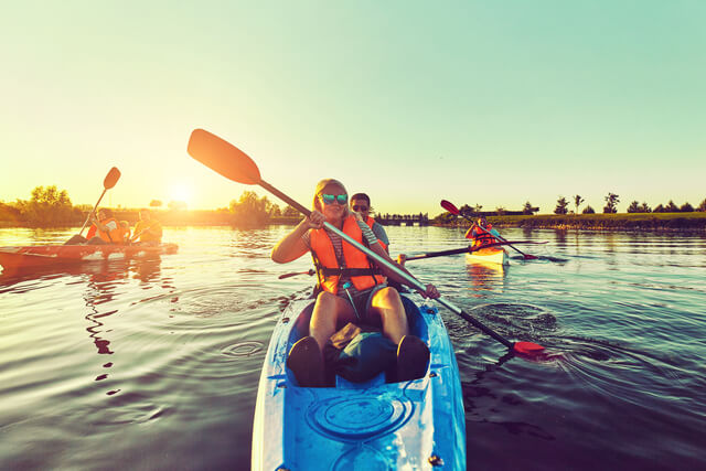 A group of people kayaking on a body of water at sunset