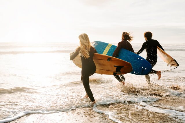 Three surfers running into the sea