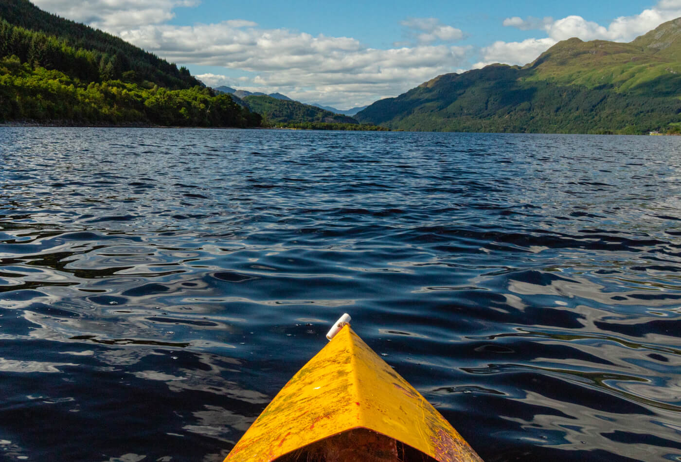 A yellow kayak sat on the water in Loch Lomond