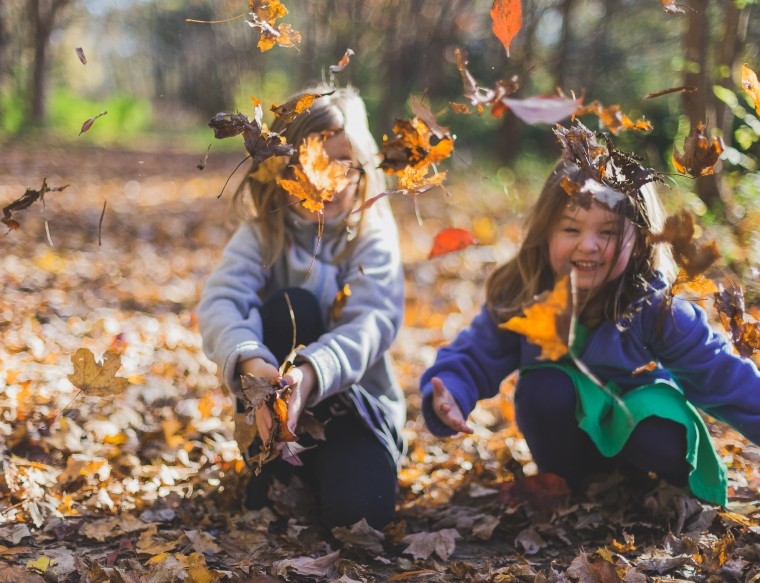Girls playing in autumn leaves 